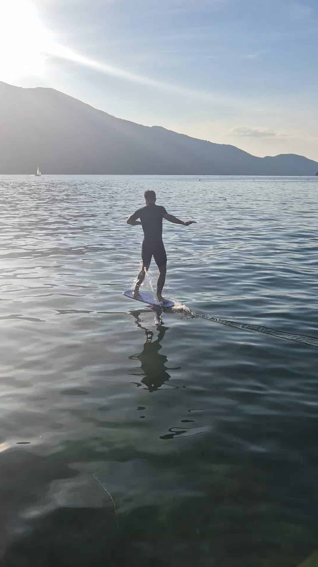 Silhouette d'un rider en pump foil au lever du jour sur le lac d'Annecy