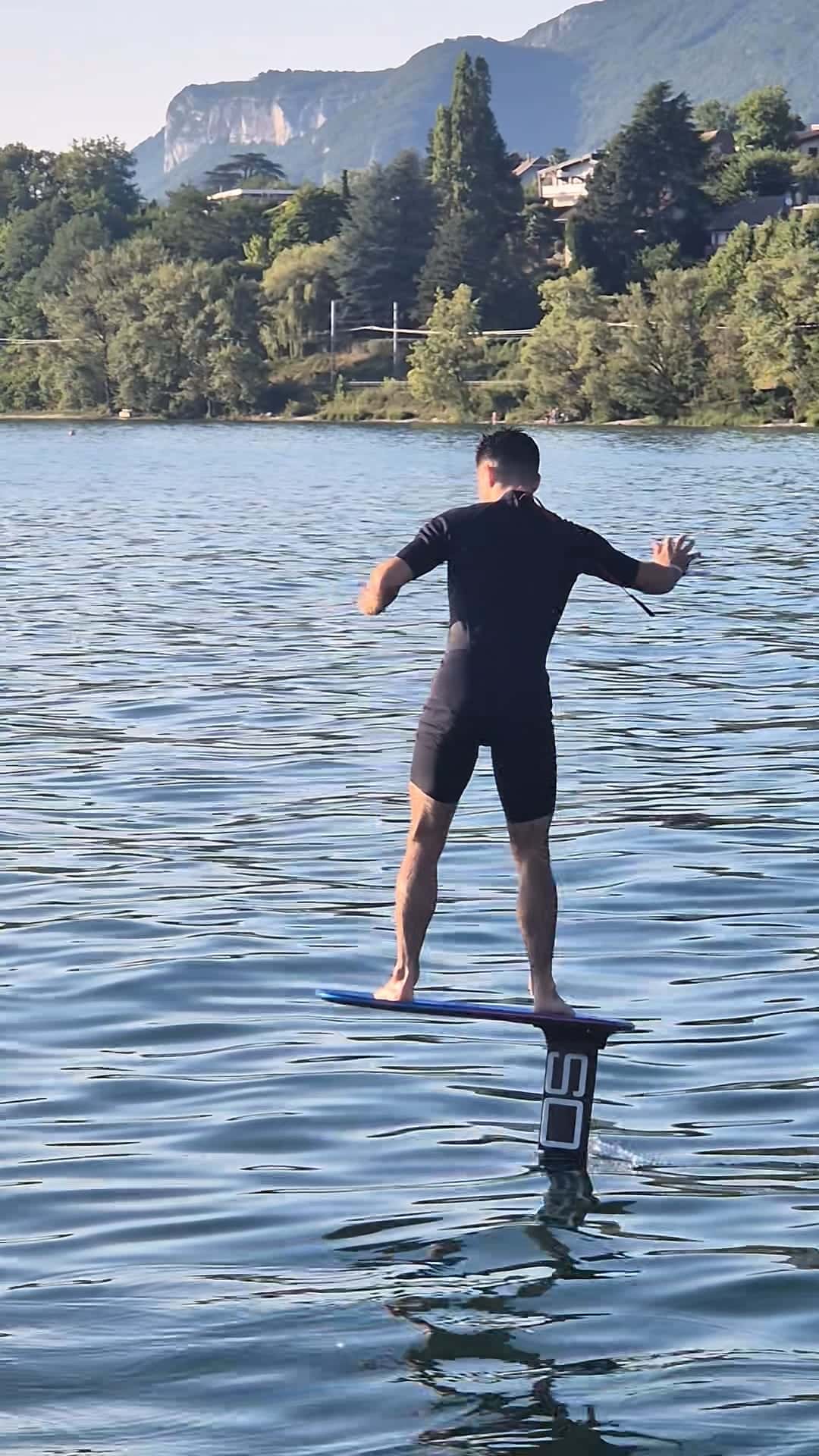 Planche de pump foil soulevée hors de l'eau par le foil sur le lac d'Annecy